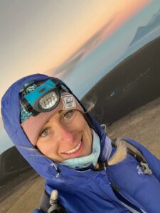 woman hiking a mountain with a headlamp