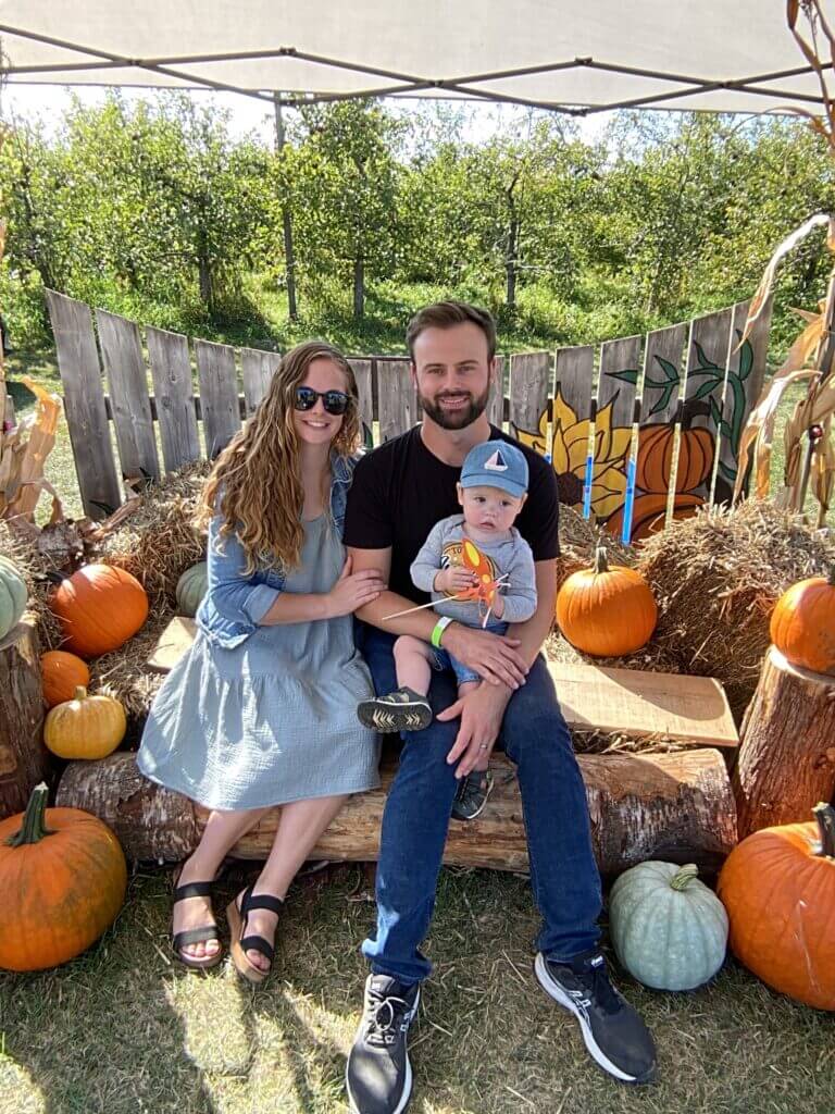 a family with a small baby posing for a fall themed photo