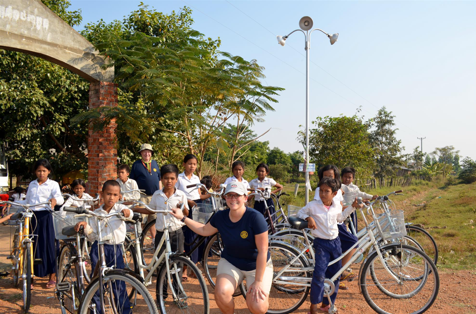 RWFL team member with uniformed students standing outside with their new bicycles. 